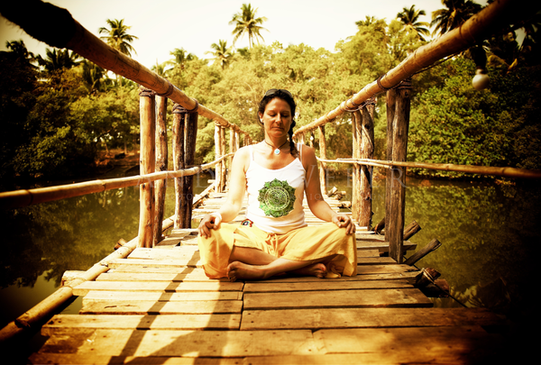 Yana Kerz sitzt im Yoga Sitz auf einer hölzernen Brücke in Indien bei Goa