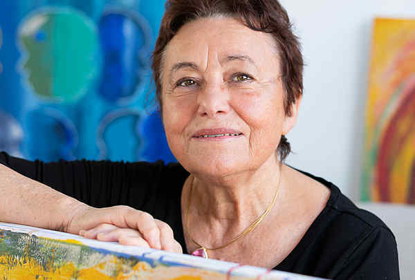 Brigitta Mahr Würzburg sitzt vor Ihren Gemälden in der Kunstgalerie BRi-MA
