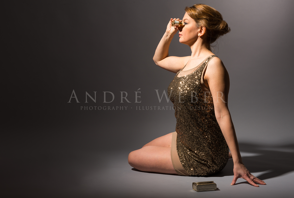Junge Frau mit Opern Fernglas sitzend am Boden auf grauem Hintergrund fotografiert, im Studio