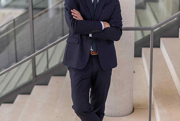 Business Foto junger hübscher Mann attraktiv, lehnt am Geländer im blauen Anzug mit Bart