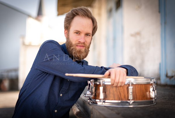 Junge Drummer mit langen Bart und Snare Drum lehnt lässig auf seiner Snare Drum an einer Rampe