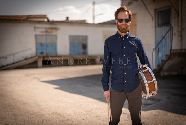 Junge Drummer mit langen Bart und Snare Drum steht lässig da.