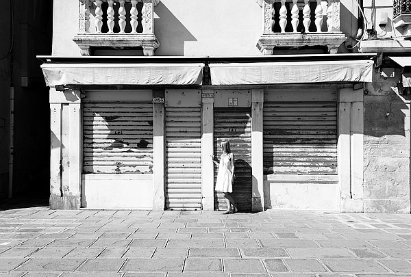 Blonde Frau mit weißen Kleid in Venedig an einem Geschäft. Schwarzweiß Foto